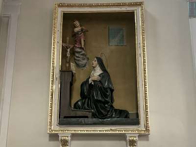 Lungo il corridoio laterale si incontrano poi due altorilievi in cartapesta realizzati nella met� del 900 da Salvatore Bruno. La prima rappresentazione mostra Santa Rita da Cascia inginocchiata davanti al Crocifisso mentre riceve la corona di spina da un angioletto